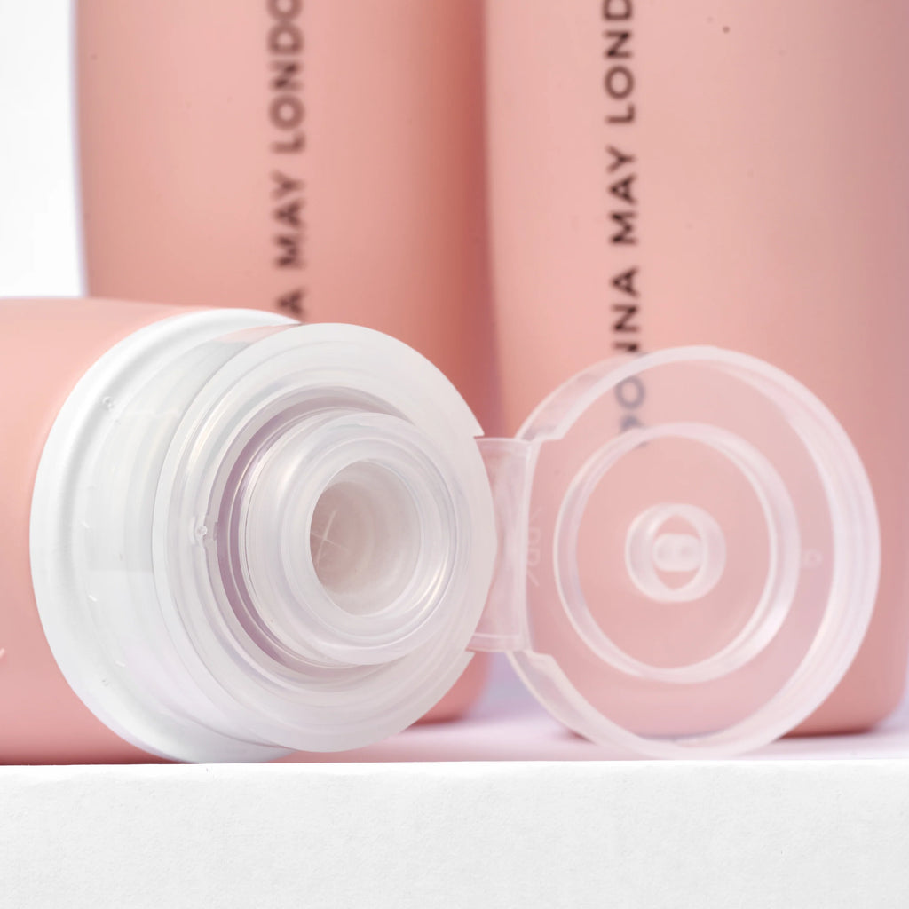 Donna May London Beauty. Pink travel set with three bottles on a bathroom counter